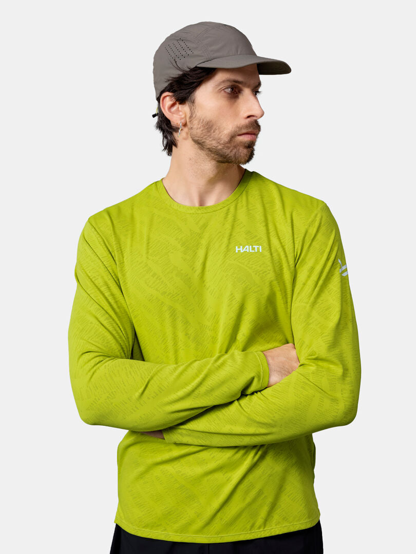 Harmaaseen lippalakkiin ja Halti Oulanka Treenipaita Miesten asuun pukeutunut mies seisoo kädet ristissä ja katsoo sivulle.