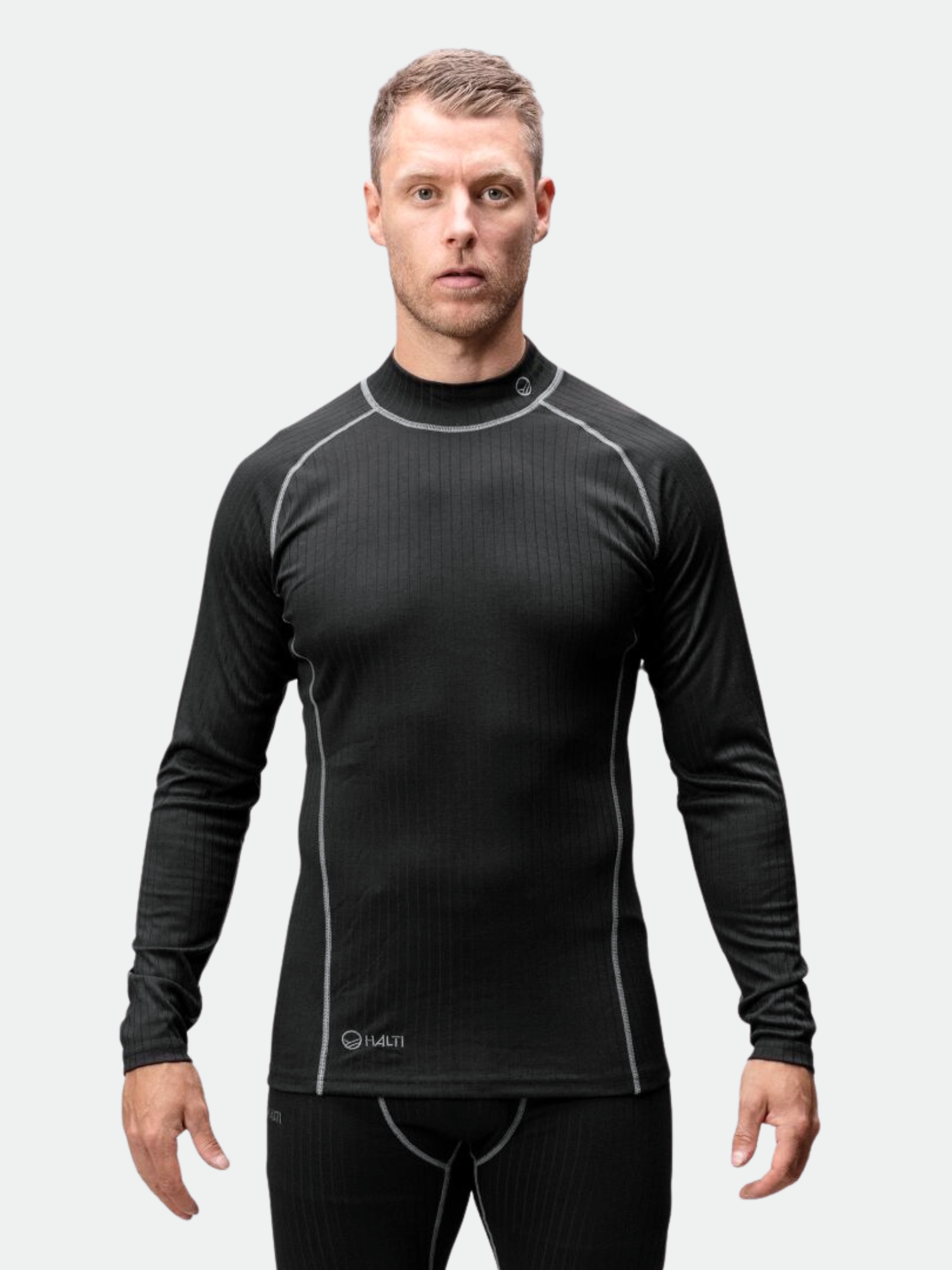 Miehellä on yllään Halti Dual Kerrasto Miesten tekninen aluskerrasto, joka on valmistettu kierrätetty polyesteristä, kasvot menosuuntaan.