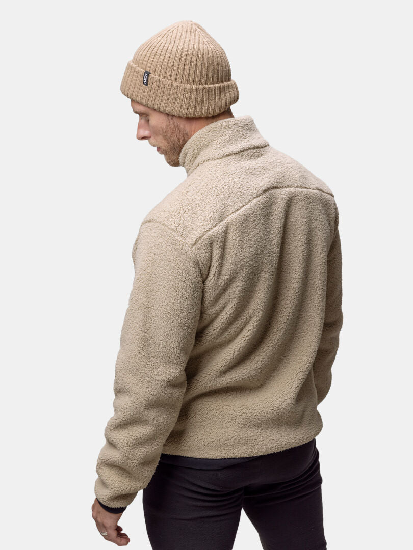 Henkilö, jolla on beige Halti Lumista Polar Fleecetakki Miesten ja neuletakki, katse poispäin kamerasta.